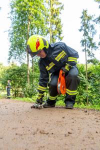 Traktor mit Heuballenpresse stürzt von einem Forstweg in den Wald